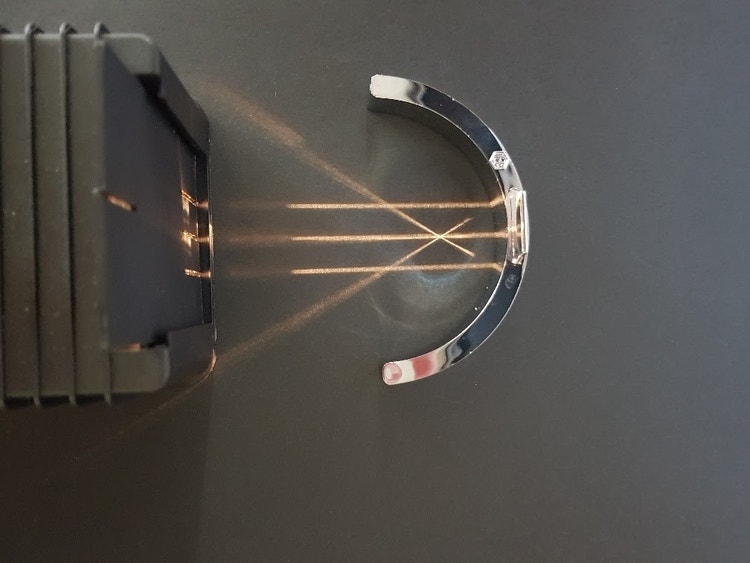 light box emitting three lines of light which is reflected back at an angle after hitting the concave mirror